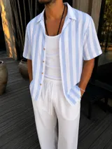 Camisa de manga corta a rayas celestes y blancas, con cuello camisero y cierre frontal de botones.