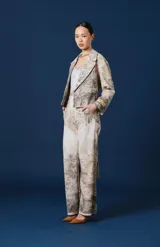 Saco Spencer de mujer, corto y de silueta relajada, con solapas amplias y bolsillos. Cuenta con un estampado estilo paisaje boscoso en tonos beige, gris y marrón, y un parche bordado con la marca en el puño izquierdo.
