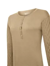 Remera de manga larga color beige, con cuello redondo y cierre frontal parcial con botones. Presenta un diseño de tejido trenzado con textura de rombos en las mangas y cuerpo liso.
