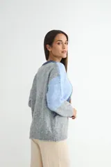 Buzo de tejido de punto con diseño de bloques de color en tonos blanco y gris, de cuello redondo y manga larga.