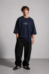 Buzo de cuello redondo en color azul marino, con mangas tres cuartos y corte oversize. Presenta un estampado tipográfico minimalista en el centro del pecho.