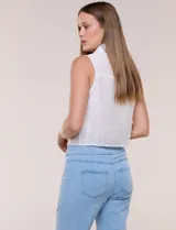 Camisa sin mangas de rayón texturado color blanco, de corte crop con cierre frontal de botones y lazos para anudar en el frente. Cuenta con cuello camisero, detalles de brillos en los hombros y bolsillos plaqué con solapa en el pecho.