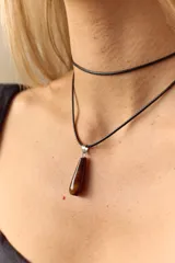 Gargantilla con tiento negro y dije de piedra natural en forma de gota con engarce de acero quirúrgico.