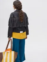 Campera de denim color marrón con cuello camisero, cierre frontal con botones y flecos en la parte superior de la espalda.