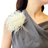 Broche de tela con forma de flor blanca y gran volumen, diseñado con múltiples tiras finas que aportan textura y movimiento.