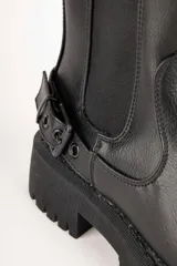 Botas de caña baja color negro, símil cuero, con pieza elastizada en sus laterales, aplique de hebilla metálica y plataforma de 5cm de alto.