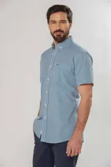 Camisa de manga corta a cuadros vichy en tonos verde y blanco, con cuello abotonado y bolsillo frontal.