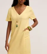 Vestido corto amarillo de viscolino, con escote en V, mangas cortas y bolsillos frontales aplicados.
