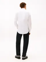 Camisa de vestir Tommy Hilfiger de color blanco, corte slim y manga larga. Presenta cuello camisero, cierre frontal con botones, puños abotonados con vuelta estampada en el interior y el logo de la marca bordado en el pecho.