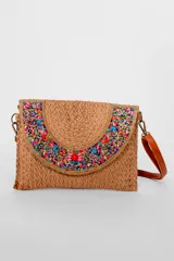 Bandolera de material tejido color marrón, con solapa decorada con canutillos y cuentas multicolores. Incluye correa larga ajustable de cuero sintético.