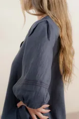 Vestido largo azul oscuro de lino 100% con escote en V, mangas abullonadas con elástico en el puño y pespunte en contraste. Presenta detalle de punto smock en el canesú y bolsillos laterales.