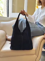 Bolso tipo tote bag negro de cuero, con costuras a la vista y manijas cortas.