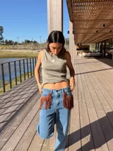 Musculosa gris oscuro de corte recto, con cuello redondo y diseño sin mangas. Presenta un pequeño bordado frontal de sol en tono amarillo y detalle de ribetes.