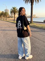 Remera negra de algodón con estampado de rostro femenino y texto "Beyond Limitis" en blanco y rosa.