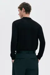 Remera polo de manga larga en punto fino negro, con cuello clásico y tapeta de tres botones. Presenta remates acanalados en puños y bajo.