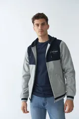Campera de felpa gris con capucha y cordón ajustable, cierre frontal con cremallera, bolsillos laterales, mangas largas y logo estampado en el pecho.