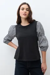 Remera de algodón negra con mangas abullonadas de tela con estampado vichy en blanco y negro, puños elásticos y cuello redondo.