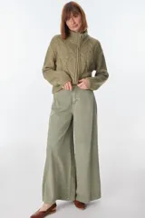 Cardigan tejido de punto grueso color gris claro con diseño de trenzas, cuello alto y cierre frontal con cremallera.