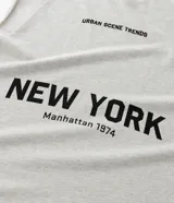 Musculosa masculina de corte boxy fit, confeccionada en algodón. Presenta cuello redondo, hombros ligeramente ampliados y acabado deshilachado en el ruedo. Cuenta con estampa frontal con la frase 'Urban Scene Trends' y el texto 'New York Manhattan 1974' en el centro.