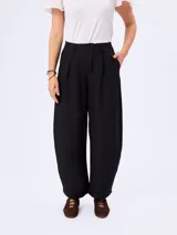 Pantalón barrel negro de corte ancho y relajado, confeccionado en poliéster con bolsillos laterales y cintura de tiro medio.