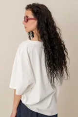 Remera blanca de manga corta y corte oversize, con bordados de motivos tropicales y marinos como palmeras, peces, estrella de mar y caracol.