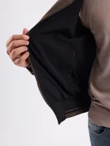 Campera reversible de gamuza sintética color marrón, con cierre frontal, cuello alto y puños de tejido acanalado con detalles de rayas.