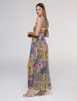 Vestido largo sin mangas de gasa color rosa, con estampado tipo patchwork tropical que incluye piñas, flamencos y motivos botánicos. Cuenta con un pronunciado escote en V y cintura elastizada.