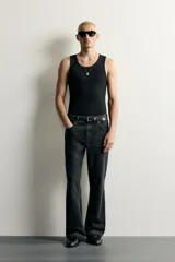 Jeans flare fit de denim negro, tiro medio, ajustados arriba y con botamanga acampanada. Cuentan con cinco bolsillos, lavado efecto gastado y bajo con acabado irregular. Cierre frontal con cremallera y botón.