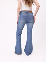 Jean de corte acampanado (flare fit) en color azul lavado, con tiro medio, cierre frontal con botón y bolsillos laterales y traseros.