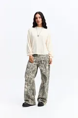 Remera de manga larga en color crema, confeccionada en tejido con textura tipo waffle. Presenta un corte relajado, cuello redondo y mangas con volumen sutil en los puños.