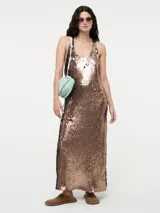 Vestido largo sin mangas, con escote en V, cubierto completamente de lentejuelas color bronce/cobre. Presenta tajos laterales en la falda.