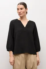 Blusa negra de manga larga con diseño de tejido plumeti y escote en V.