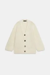 Chaqueta de punto de lana con cuello en pico, manga larga y cierre frontal con botones oscuros. Presenta un diseño de tejido grueso y holgado.