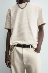 Camiseta de manga corta color crema, con cuello redondo y tejido texturizado con estructura.