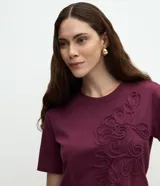 Remera de algodón color bordó con cuello redondo, mangas cortas y diseño de bordado floral en relieve en la parte delantera.
