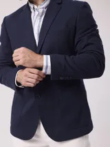 Saco color beige de piqué con cuello con solapas y bolsillos de plastrón. Mangas con coderas y bajo con abertura en espalda.