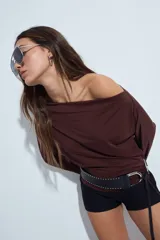 Top de manga larga con escote bote amplio, diseñado para usar ligeramente caído sobre los hombros. Presenta una silueta entallada y tejido liso, liviano y adaptable al cuerpo.