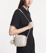 Bolso floater pequeño estructurado, color dorado, con cierre doble, texturizado, con correa transversal ajustable y tirador de pompón.