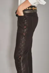 Pantalon de cuero ovino color marron, de corte bootcut, con detalle de cordones cruzados a lo largo de las costuras laterales y cierre de ojalillos metalicos.