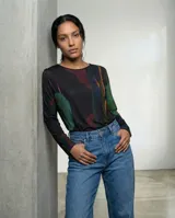 Remera de manga larga con cuello redondo, confeccionada en tejido elástico y liviano. Presenta un estampado abstracto inspirado en texturas orgánicas en tonos oscuros, verdes y rojizos.