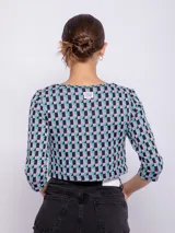 Top corto negro con estampado de líneas onduladas blancas, mangas 3/4 y abertura circular en el pecho.