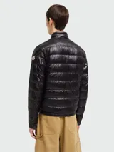 Campera puffer corta Moncler modelo Acorus, color negro, con cuello alto, cierre frontal y bolsillos laterales con cierre.