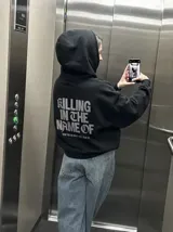 Canguro negro con capucha y bolsillo tipo canguro, de corte regular y confección en mezcla de algodón y poliéster. En la parte posterior presenta una estampa grande en tono gris con la inscripción "Killing in the name of" y una frase complementaria.