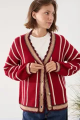 Cardigan de punto a rayas verticales en tonos rojo, blanco y marrón, con escote en V, mangas largas y cierre frontal de botones. Presenta terminaciones con detalles de ondas y bordados en los bordes.