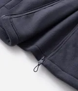 Buzo de fleece color verde agua con capucha ajustable, cierre frontal completo y bolsillo con cierre en el pecho. Presenta un diseño funcional con recortes en tejido plano y calce regular.
