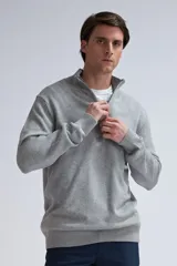 Buzo de punto gris claro melange con cuello alto y medio cierre.
