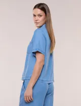 Camisa de corte recto y calce fluido color celeste, confeccionada en lyocell, con cuello camisero clásico, mangas cortas y bolsillos plaqué en el pecho.