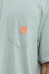 Remera color arena de corte holgado con bolsillo en el pecho y logo estampado en azul.