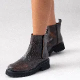 Bota corta estilo chelsea de cuero vacuno negro con acabado desgastado en tono marrón en la puntera y laterales. Presenta elástico lateral, cierre interno y suela de goma tipo track con plataforma.