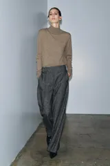 Pantalón de corte recto confeccionado en tejido con mezcla de lana. Presenta tiro medio, cintura con trabillas, bolsillos laterales y traseros, y detalle de nervio frontal. Cierre mediante cremallera, botón y ganchos metálicos.